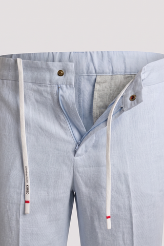 Light blue pants with a close-up of the waistband and side seam on a light gray background.